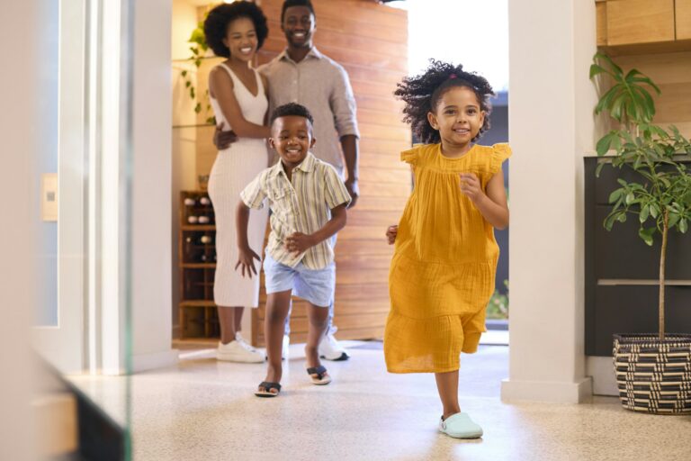 Family Returning Home Opening Front Door And Children Running In