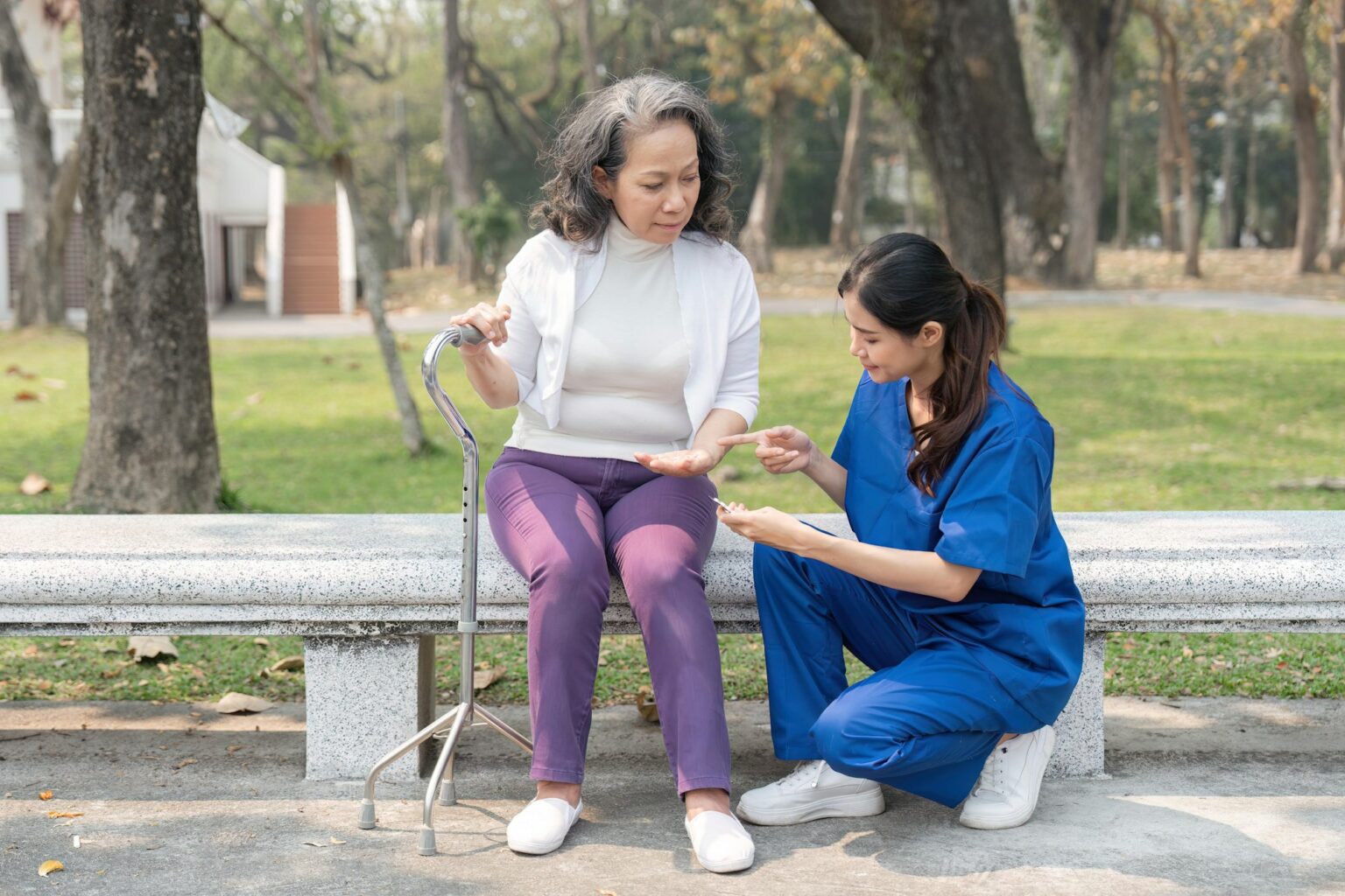 Nurse giving medicine to senior woman at hospital park, Maintenance