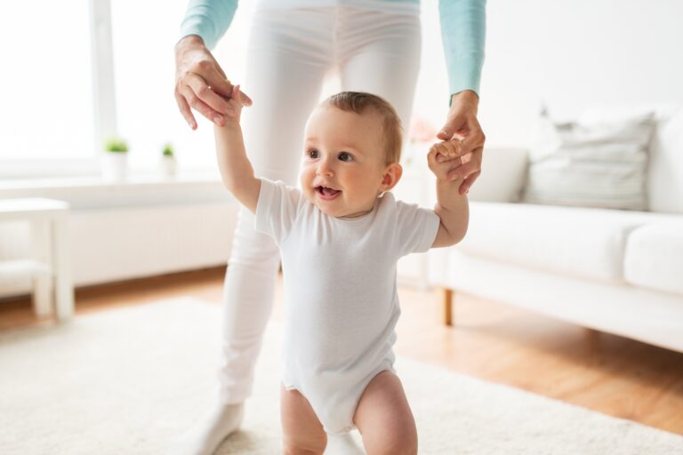 happy baby learning to walk with mother help