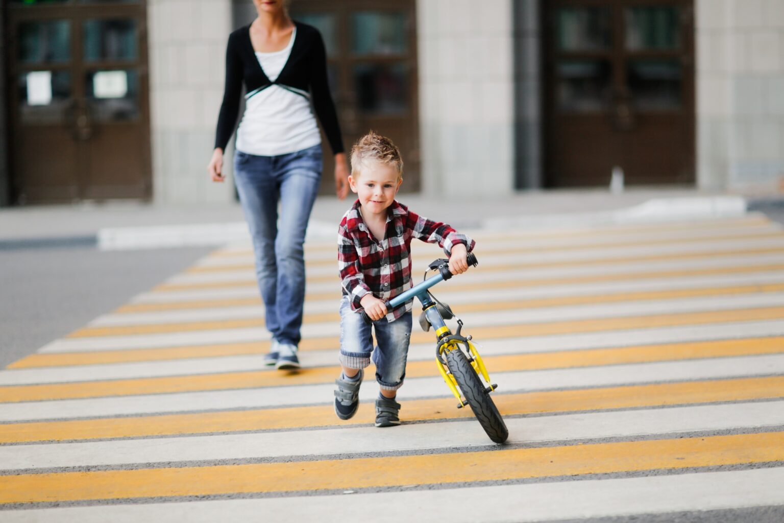 cute young mother with 3-year-old son crosses the road at pedestrian crossing