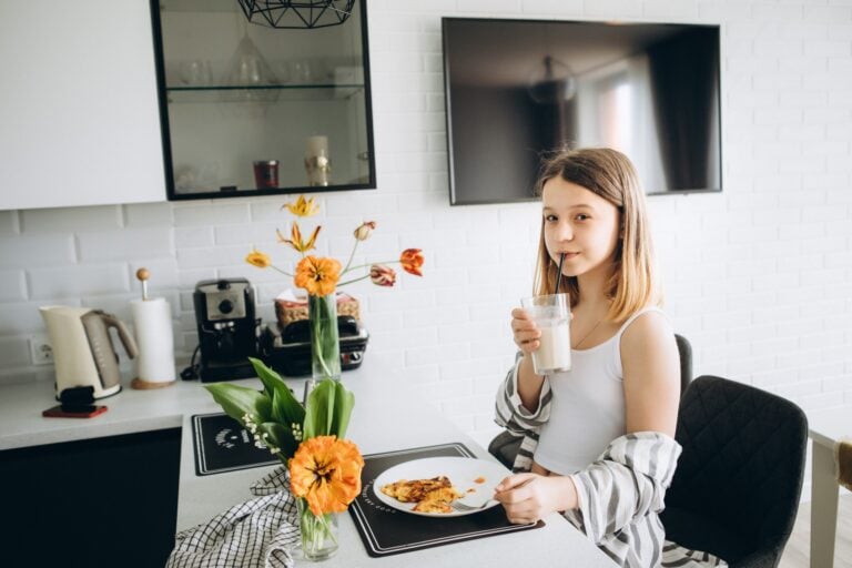 11-year-old girl is having breakfast in the kitchen.